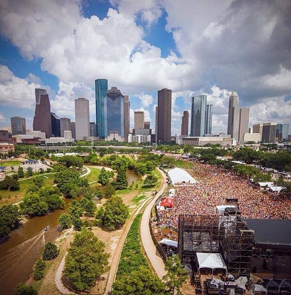 Aerial view of Free Press Summer Fest crowds and stages at Eleanor Tinsley Park with the downtown Houston skyline